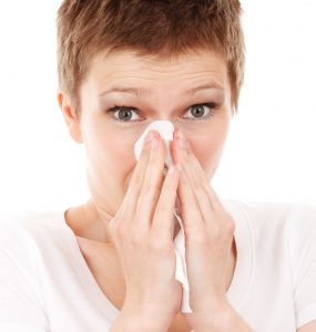 Woman with short hair holding a tissue about to blow her nose