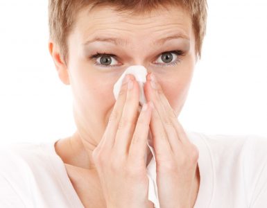 Woman with short hair holding a tissue about to blow her nose