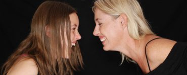 Two woman smiling and looking at each other leant over