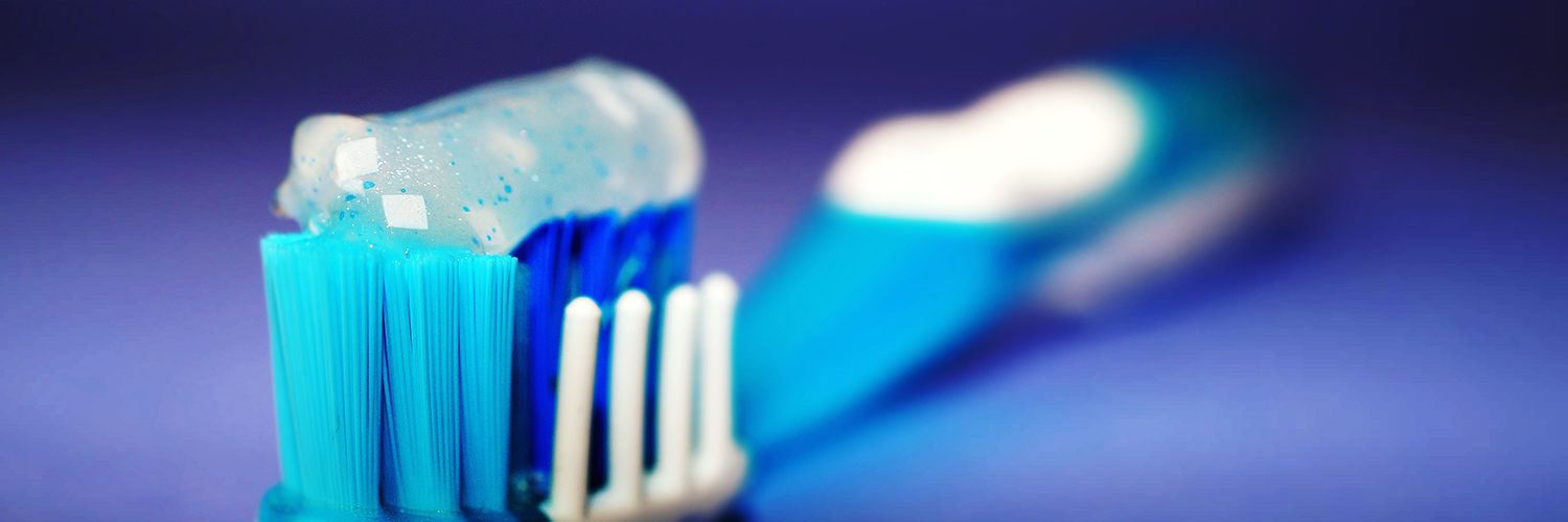 A toothbrush with toothpaste on it in front of a rich blue background