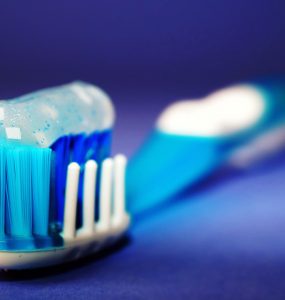 A toothbrush with toothpaste on it in front of a rich blue background