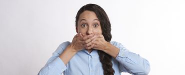 woman standing hands covering mouth